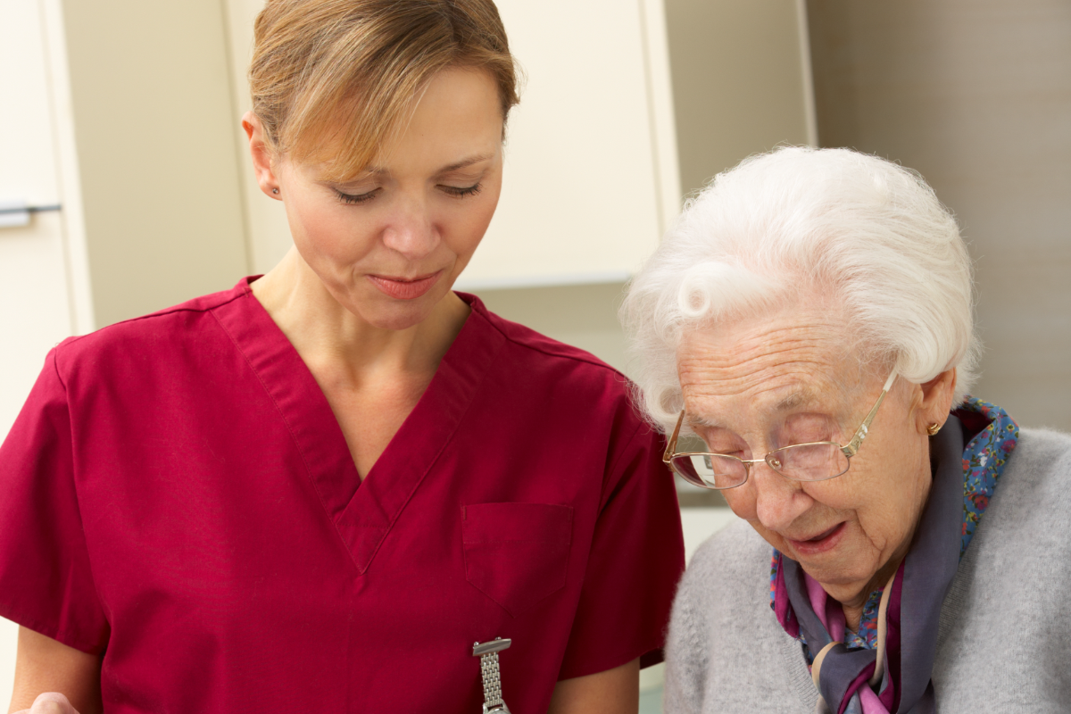 Caregiver helping an older woman with a meal in her kitchen