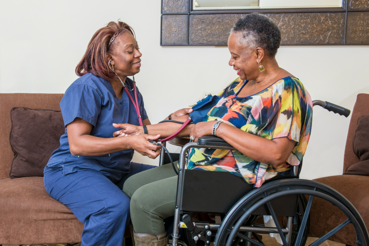 Home health nurse checking an older woman's blood pressure in her living room