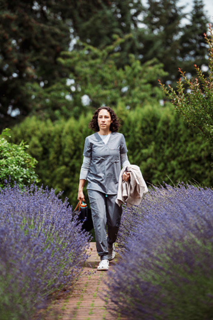 Field clinician in scrubs walking outdoors between home visits