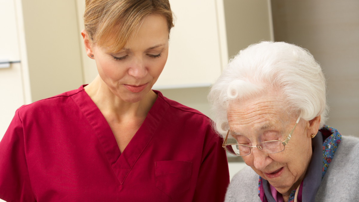 Caregiver helping an older woman with a meal in her kitchen