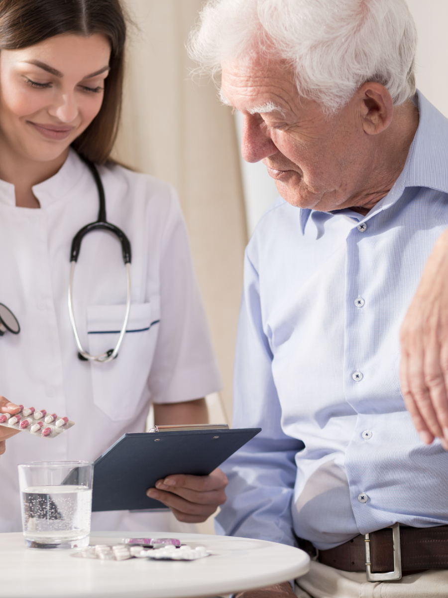 Nurse reviewing medications and a chart with an older man standing at his walker