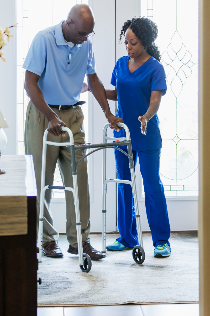 Nurse guiding an older man using a walker indoors during gait training
